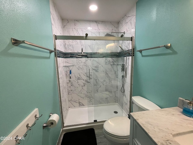 bathroom featuring toilet, a shower with door, and vanity