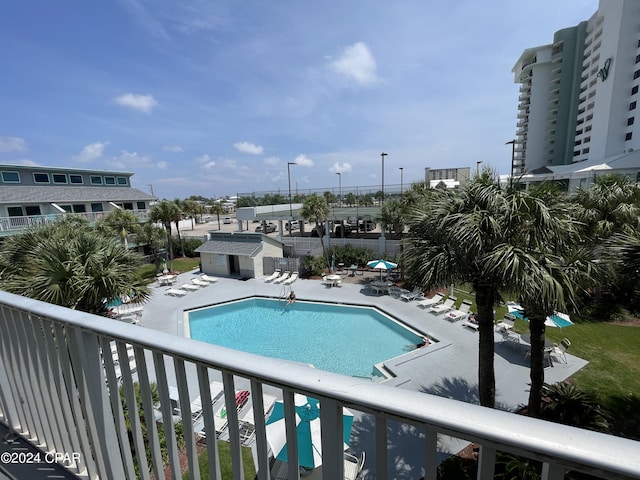 community pool with a patio area, an outdoor structure, and fence