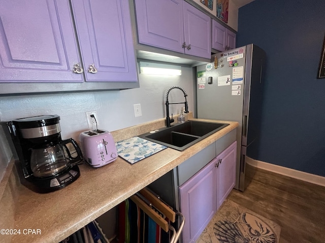kitchen featuring a sink, wood finished floors, freestanding refrigerator, light countertops, and baseboards
