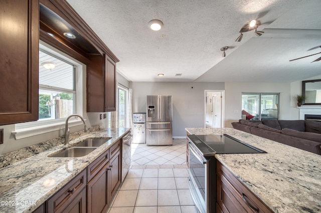 kitchen featuring light tile patterned floors, appliances with stainless steel finishes, a ceiling fan, open floor plan, and a sink