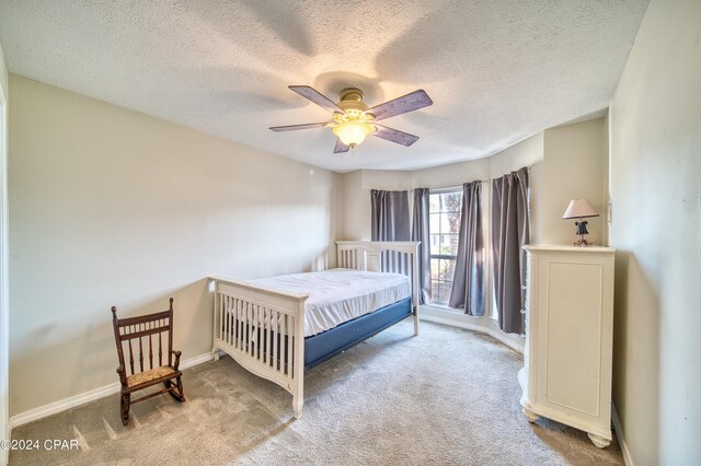 bedroom with a textured ceiling, ceiling fan, and light carpet