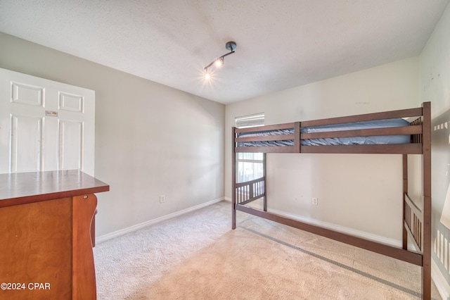 unfurnished bedroom featuring light carpet, a textured ceiling, and track lighting