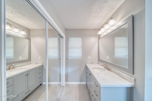 bathroom with dual vanity, a textured ceiling, and tile patterned floors