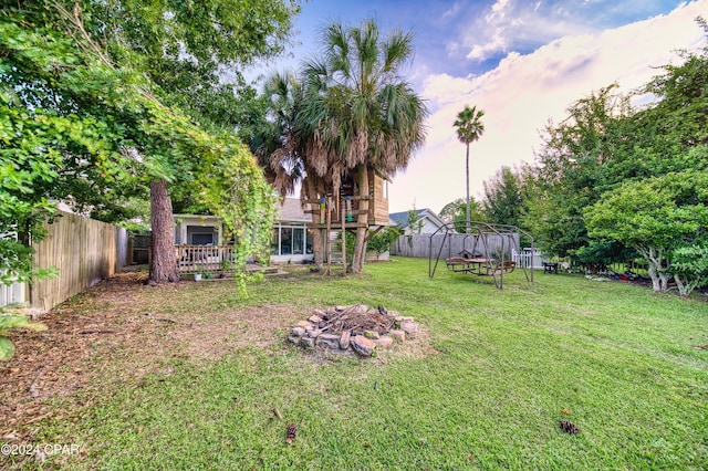 view of yard featuring a deck, a fenced backyard, and a fire pit