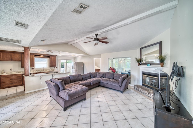 living room with lofted ceiling with beams, light tile patterned floors, visible vents, and a glass covered fireplace