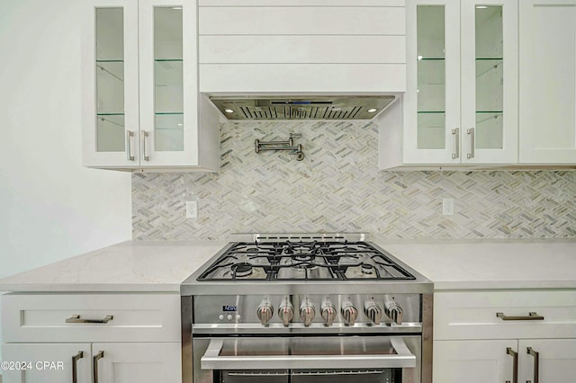 kitchen with white cabinets, extractor fan, and stainless steel stove