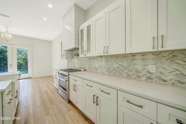 kitchen with high end stainless steel range oven, light hardwood / wood-style floors, decorative backsplash, and white cabinets