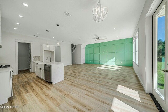 kitchen with light wood-type flooring, stainless steel dishwasher, an island with sink, pendant lighting, and white cabinets