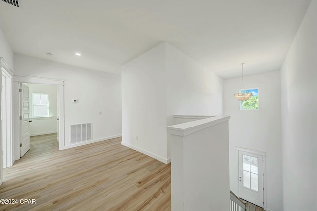 empty room featuring a chandelier and light hardwood / wood-style flooring