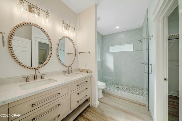 bathroom with wood-type flooring, toilet, a shower with door, and vanity