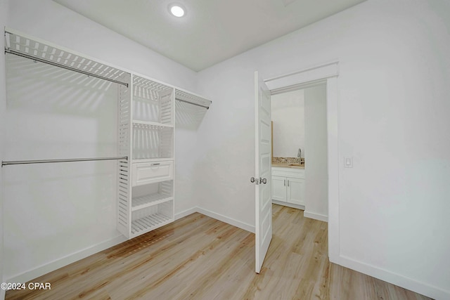 walk in closet with light hardwood / wood-style flooring