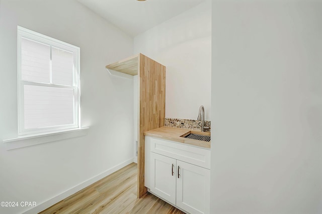 bar featuring white cabinetry, sink, and light hardwood / wood-style flooring