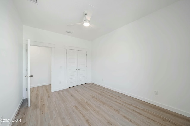 unfurnished bedroom with ceiling fan, a closet, and light wood-type flooring