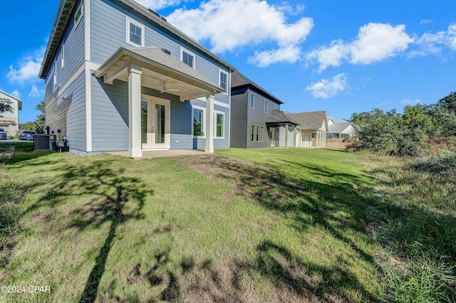 back of property with central AC, a yard, and french doors