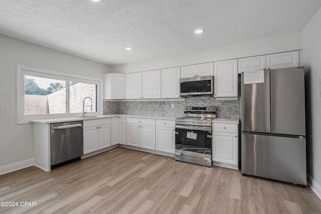 kitchen featuring sink, stainless steel appliances, light hardwood / wood-style flooring, and white cabinetry