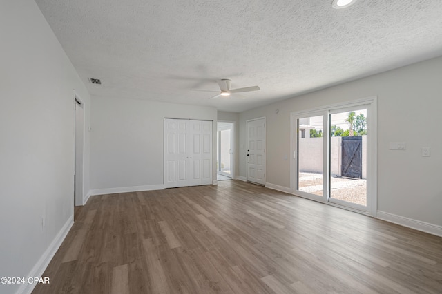 unfurnished bedroom with access to outside, hardwood / wood-style flooring, a textured ceiling, and ceiling fan