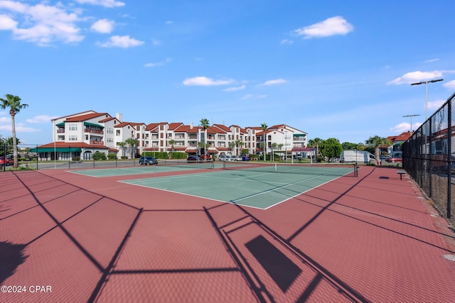 view of tennis court with community basketball court and fence