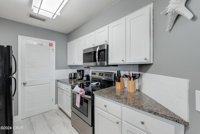 kitchen with marble finish floor, visible vents, appliances with stainless steel finishes, white cabinets, and dark stone counters