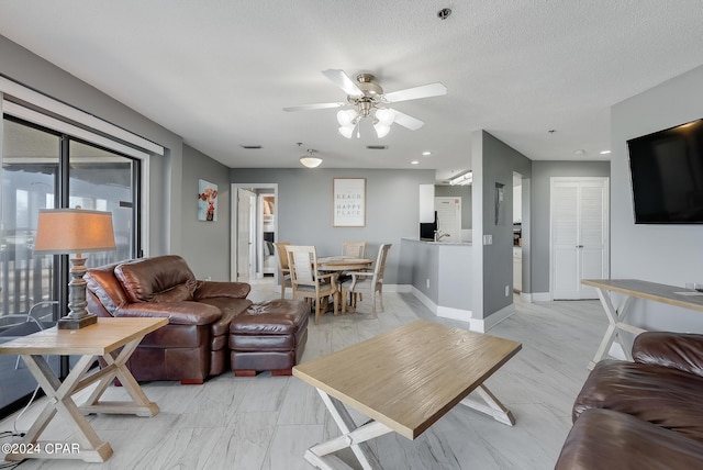 living room featuring a textured ceiling, ceiling fan, visible vents, and baseboards