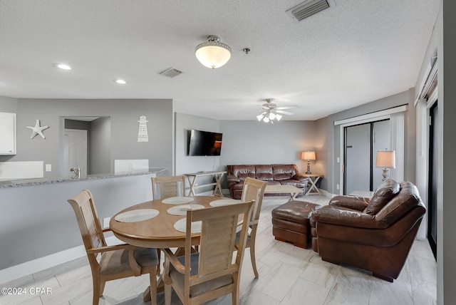 dining space featuring visible vents, ceiling fan, a textured ceiling, and baseboards