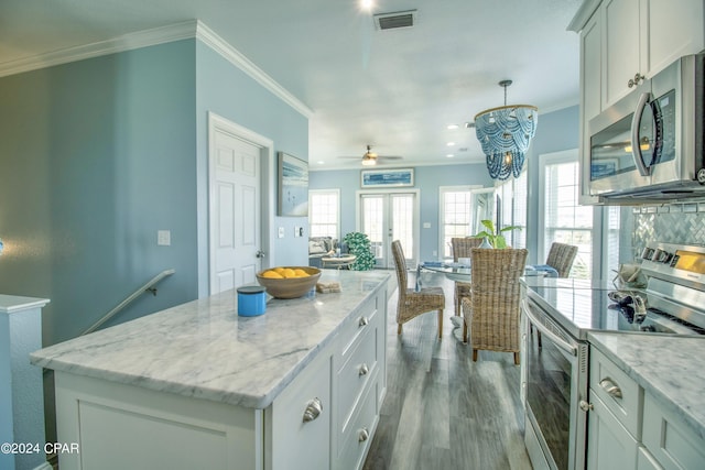 kitchen featuring appliances with stainless steel finishes, light hardwood / wood-style flooring, crown molding, a kitchen island, and ceiling fan