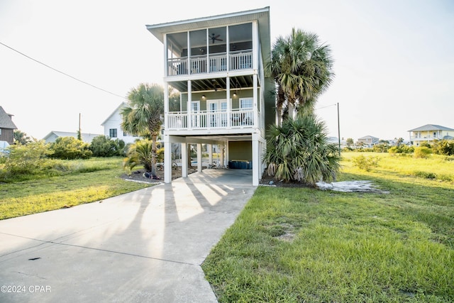 coastal inspired home featuring driveway, a balcony, a carport, and a front yard