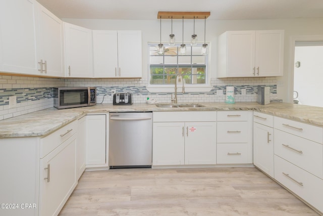 kitchen with decorative light fixtures, sink, white cabinets, and stainless steel appliances