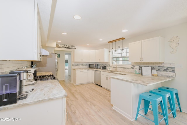 kitchen featuring kitchen peninsula, white cabinets, a breakfast bar, and dishwasher