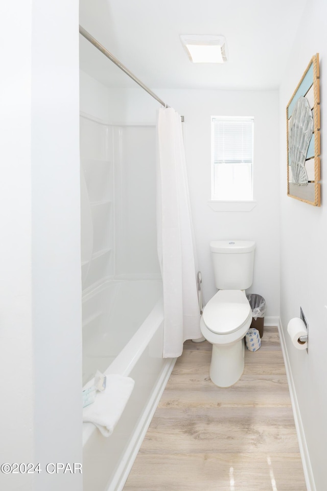 bathroom with hardwood / wood-style floors, toilet, and shower / bath combination with curtain