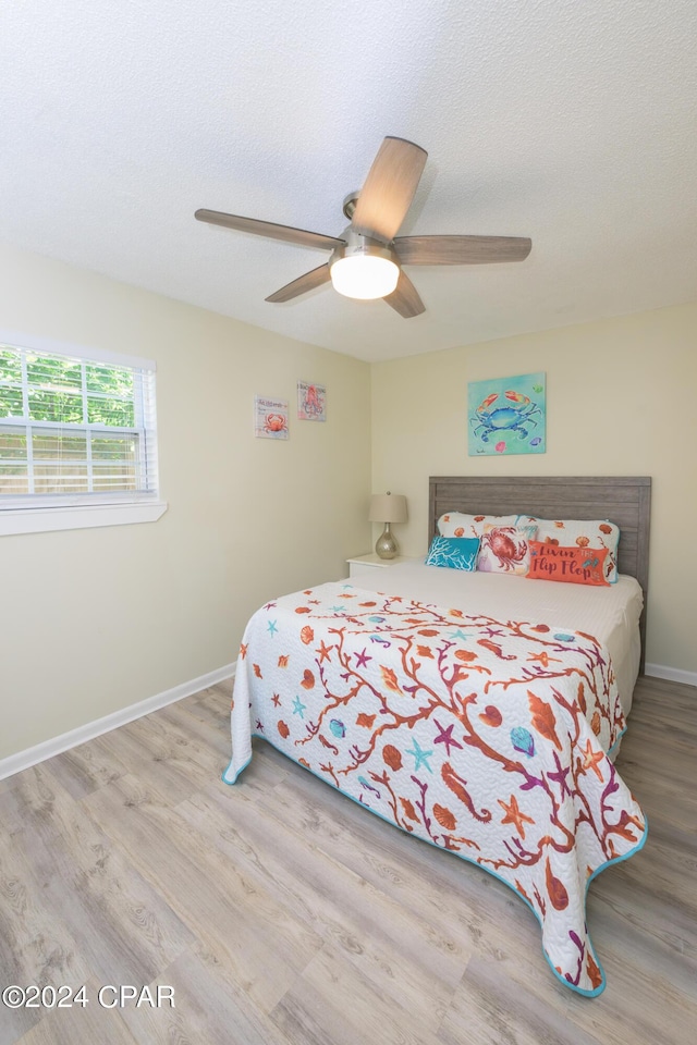 bedroom with ceiling fan, a textured ceiling, and light hardwood / wood-style flooring