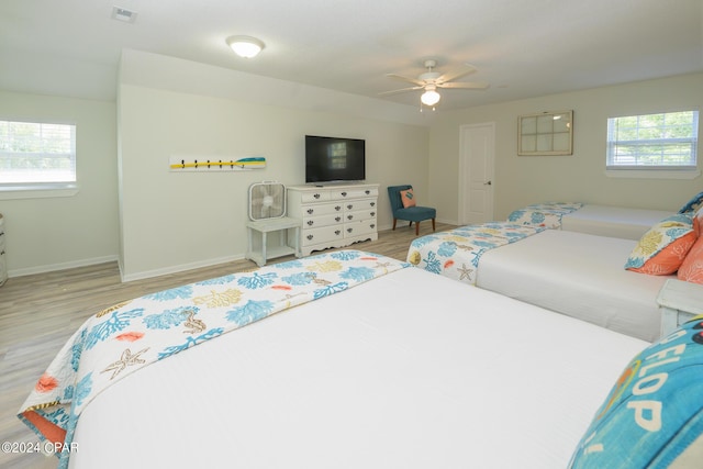 bedroom with ceiling fan, multiple windows, and light hardwood / wood-style floors