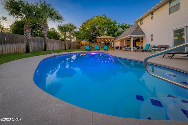 pool at dusk featuring a gazebo and a patio area