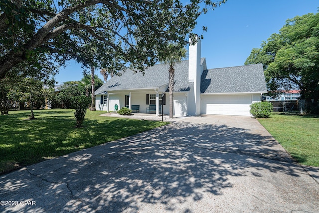 view of front of property featuring covered porch, a garage, and a front lawn