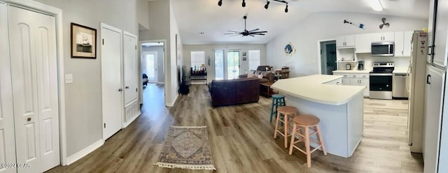 kitchen with white cabinetry, stainless steel appliances, a kitchen breakfast bar, and hardwood / wood-style floors