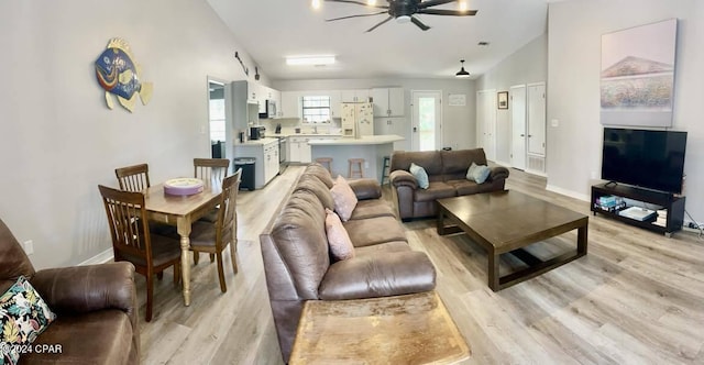 living room with ceiling fan, lofted ceiling, and light wood-type flooring