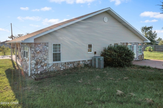 view of side of home with central air condition unit and a lawn