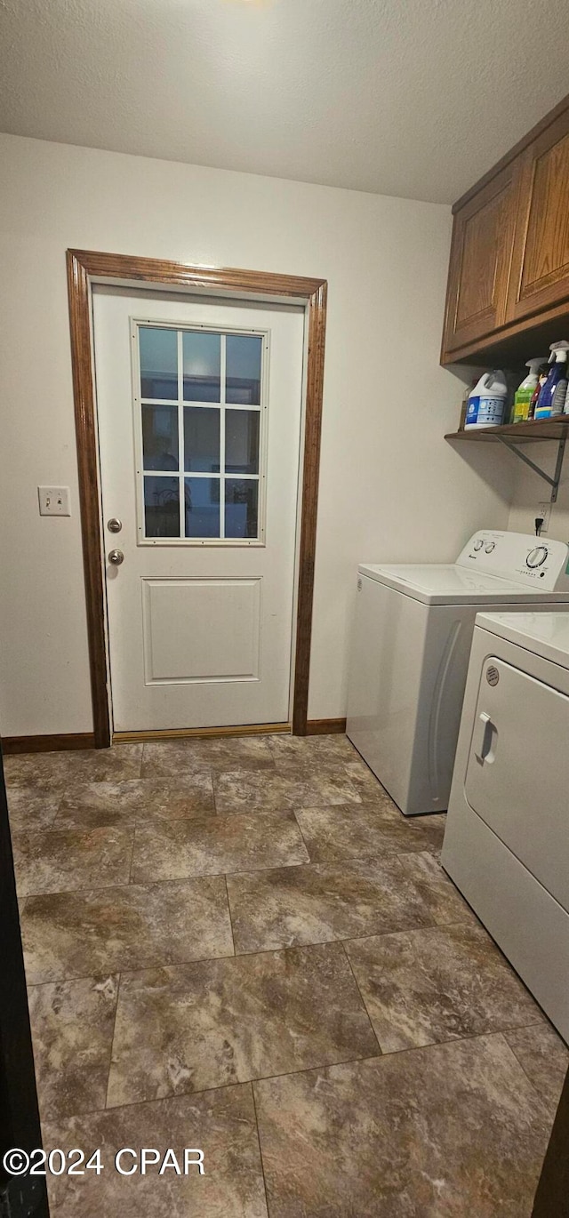 laundry area with a textured ceiling, washing machine and dryer, and cabinets