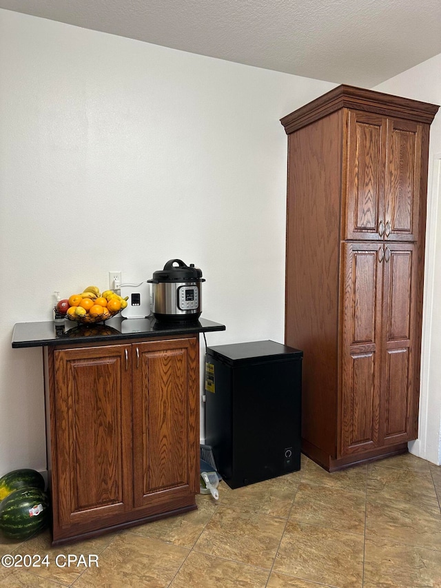 bar with fridge and light tile patterned floors