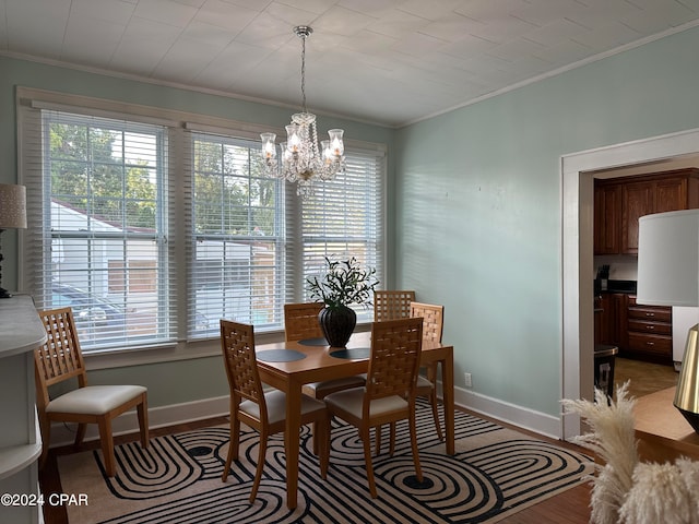 dining area with hardwood / wood-style flooring, an inviting chandelier, and ornamental molding