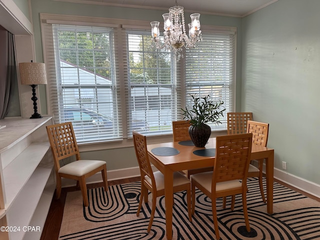 dining area with an inviting chandelier, ornamental molding, and wood-type flooring