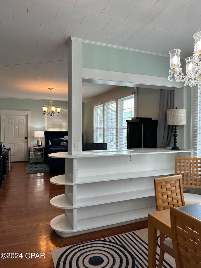 living room with hardwood / wood-style flooring, an inviting chandelier, and crown molding