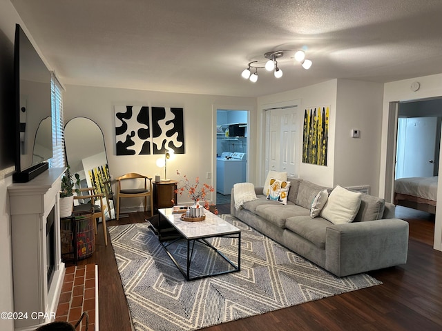 living room featuring a textured ceiling, washer / dryer, and dark wood-type flooring