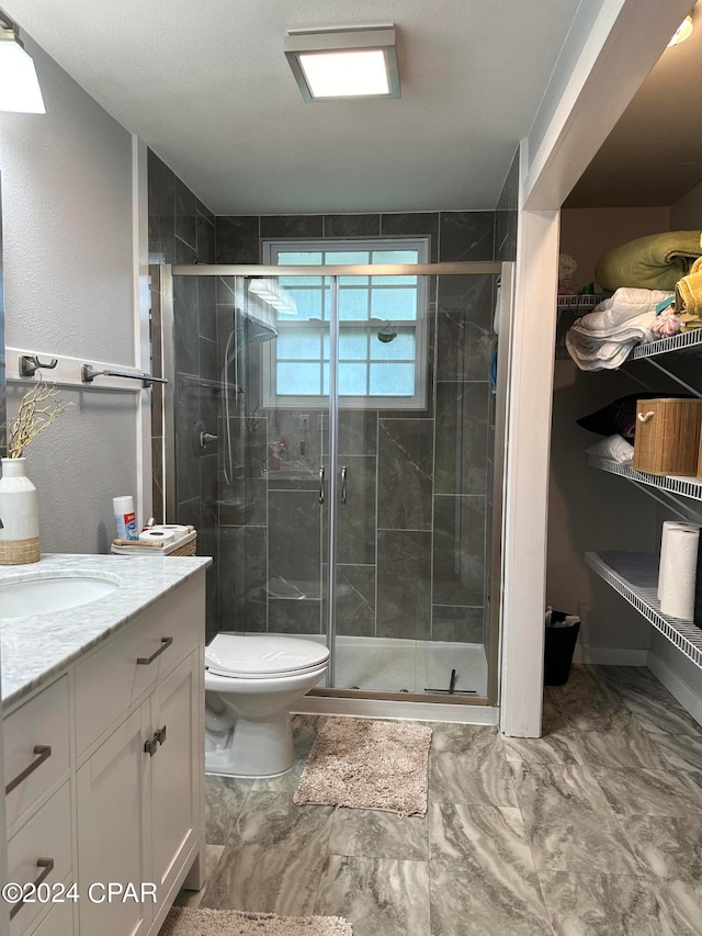 bathroom featuring tile patterned flooring, a shower with door, vanity, and toilet