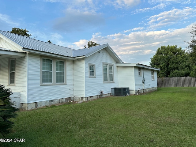 view of side of home with central air condition unit and a lawn