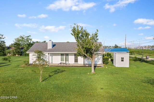 back of house with a storage shed and a lawn