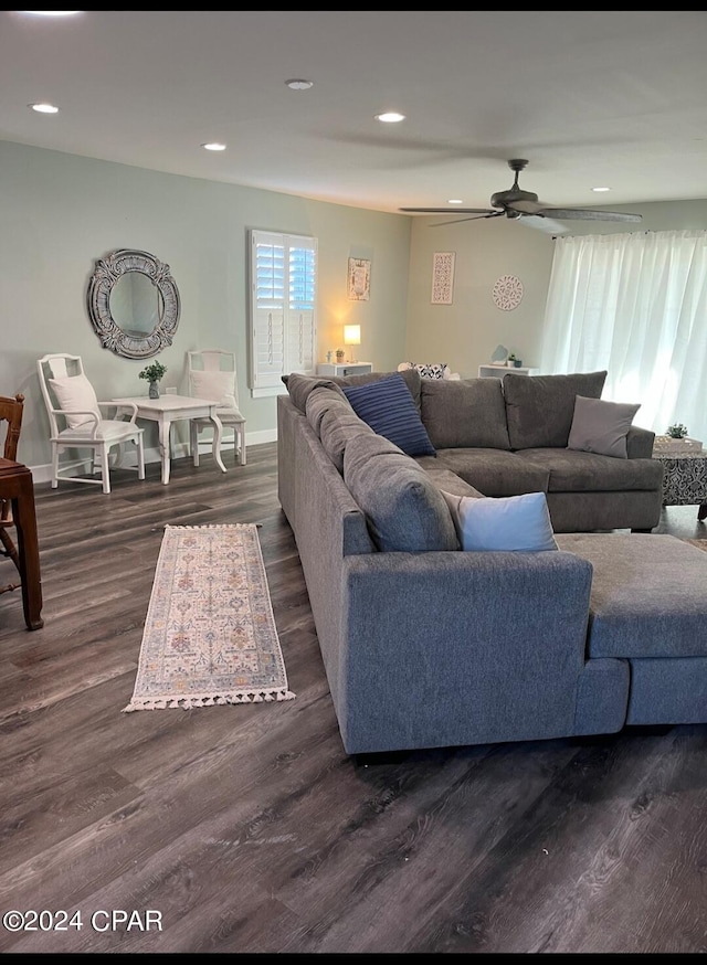 living room featuring ceiling fan and dark wood-type flooring