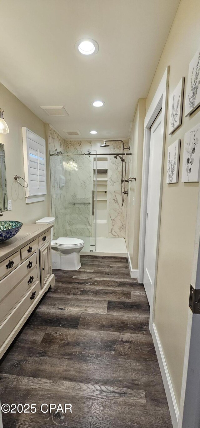 bathroom with vanity, hardwood / wood-style flooring, a shower with door, and toilet