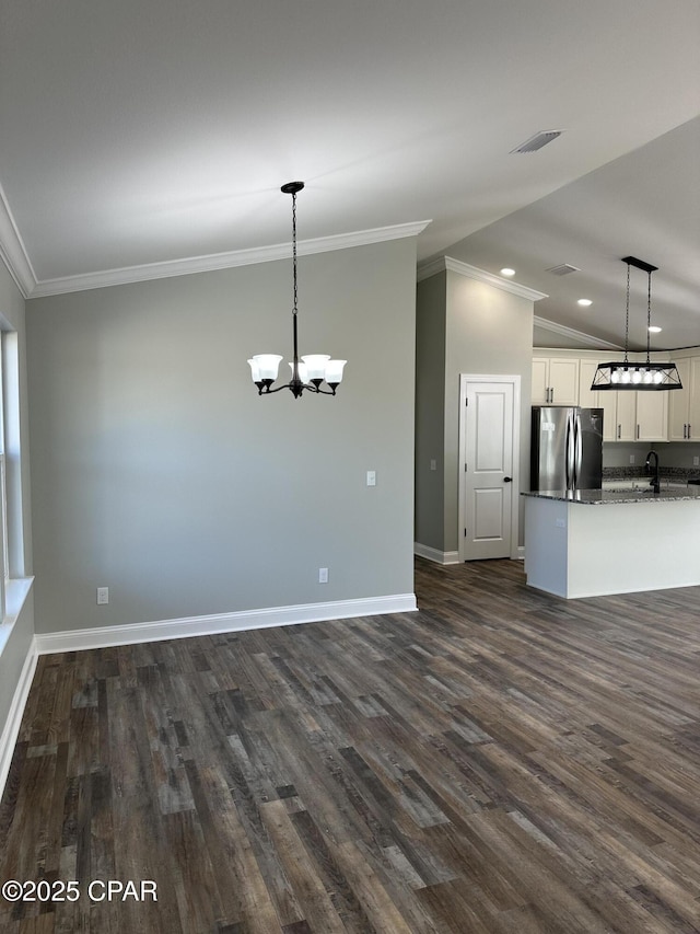 interior space featuring dark hardwood / wood-style flooring, crown molding, a chandelier, and vaulted ceiling