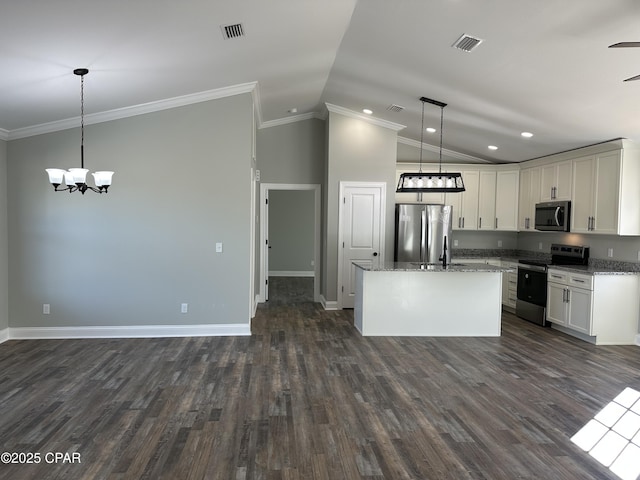 kitchen with pendant lighting, appliances with stainless steel finishes, a center island, and vaulted ceiling