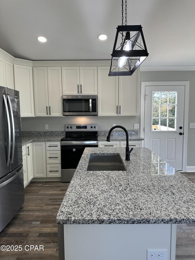 kitchen with sink, white cabinets, appliances with stainless steel finishes, and a center island with sink